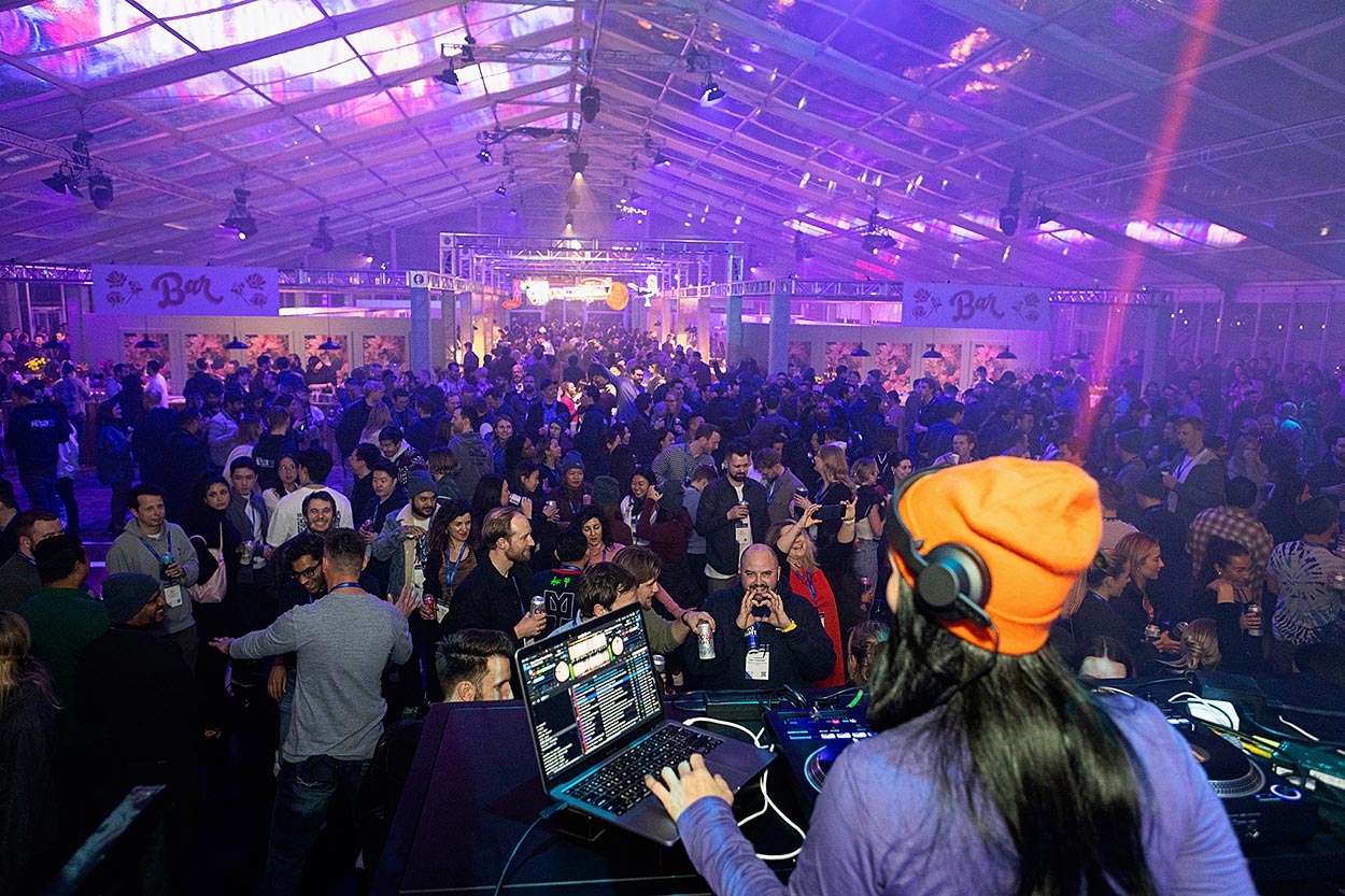 view from behind DJ of a large dance party
