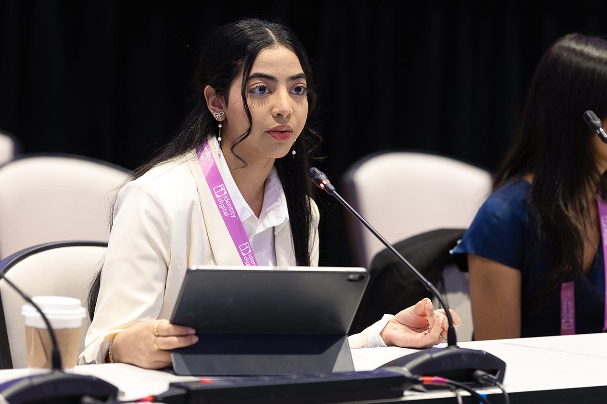 A young woman speaking into a mic, with a computer in front of her