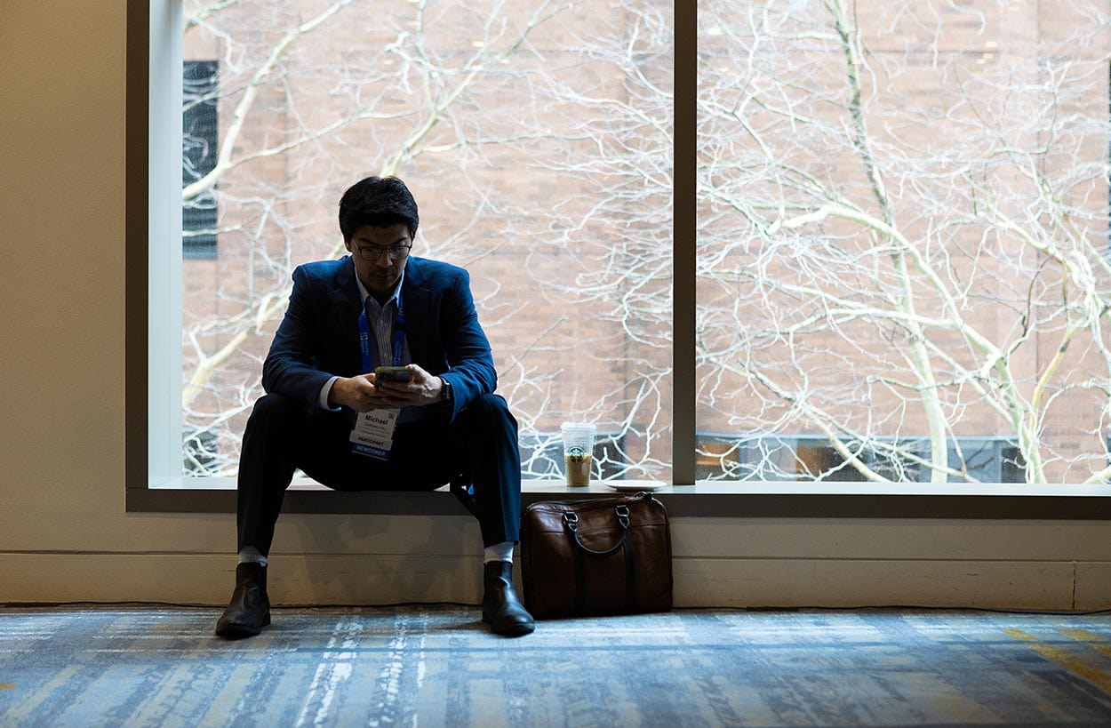 silhouette of a man near a window, on his cell phone