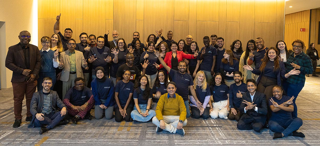 young people at a conference some seated some smiling and waving
