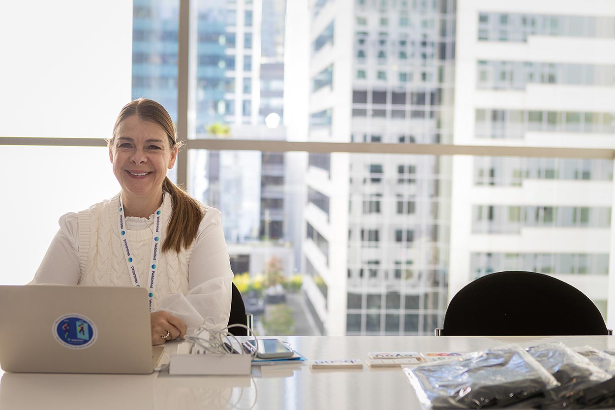 Smiling woman at computer with city skyline behind her
